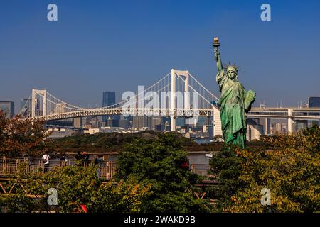 Landschaftsbild der tokyo Freiheitsstatue im Vordergrund vor der Regenbogenbrücke und der Hafenpromenade von tokio Stockfoto