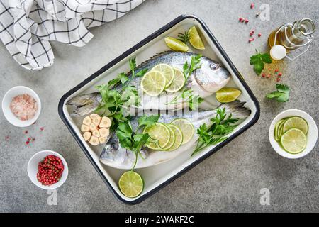 Roh frisch. Frischer roher dorado mit Zitrone, Limette, Petersilie und Salz auf altem grauen Betonhintergrund bereit zum Kochen. dorado, dorado. Meeresfrüchte, gesund Stockfoto