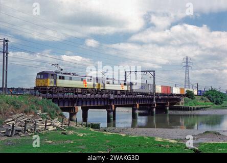 Ein Paar Elektrolokomotiven der Baureihe 86 der Nummern 86609 und 86635, die am 15. Juni 1993 einen gut beladenen freightliner über den Fluss Stour bei Manningtree fuhren. Stockfoto