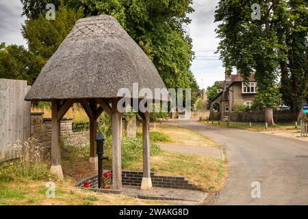 Großbritannien, England, Oxfordshire, Fringford, Main Street, Wasserpumpe mit Strohdach Stockfoto