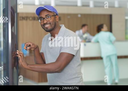 Mann repariert Automaten mit Schraubenzieher im Krankenhaus Stockfoto