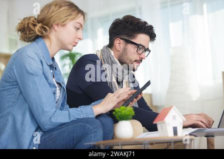 Ein junges glückliches Paar auf dem Sofa, das die Finanzen überprüft Stockfoto