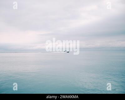 Ein kleines Schiff, das an einem bewölkten Tag durch abgehacktes Wasser segelt, ohne dass andere Schiffe in Sicht sind. Stockfoto