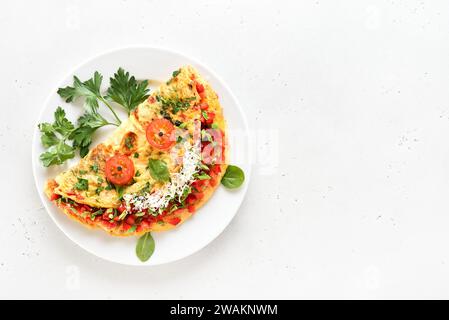 Gefülltes Omelette mit roter Paprika und grüner Zwiebel auf Teller über Steinhintergrund mit Kopierraum. Draufsicht, flach Stockfoto