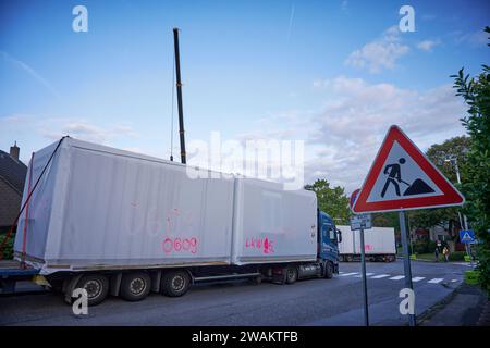 In Essen baut der Bauverein Kettwig in Ickten neu. Die Bauweise besteht aus Fertigbauteilen. Tieflader bringen Fertigbauteile zu einer Bause Stockfoto