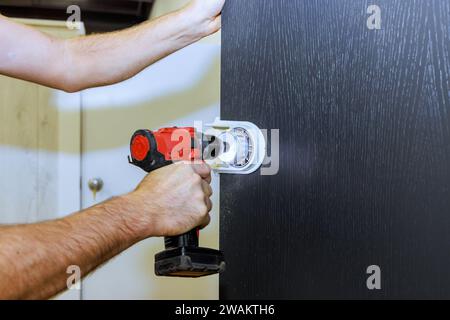 Handwerker bohren Löcher für Verriegelungsgriffe in Holztüren Stockfoto