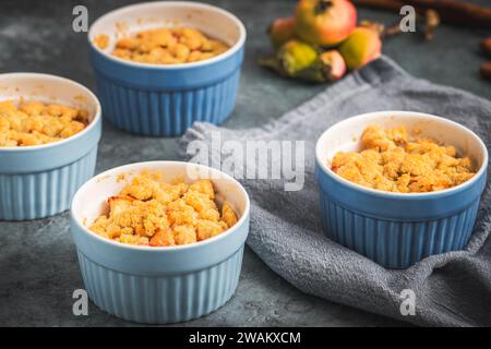 Apfelbrösel in kleinen blauen Formen auf einem rustikalen grauen Tisch Stockfoto