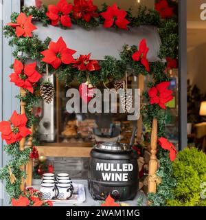 Tisch zum Verkauf von Glühwein, Dekoration in Form einer Weihnachtsgirlande, Becher für Glühwein. Weihnachtliche Atmosphäre im Café. Thermopot. Stockfoto