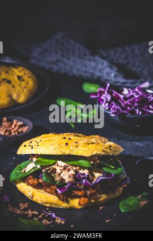 Hausgemachter veganer Döner Burger in Kürbisfladenbrot gefüllt mit Sojafleisch, Rotkohl, Spinat und Kürbissauce. Stockfoto