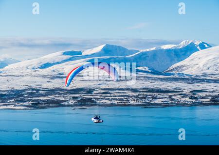 Gleitschirmflieger fliegen im Winter über die norwegische Stadt Tromso Stockfoto