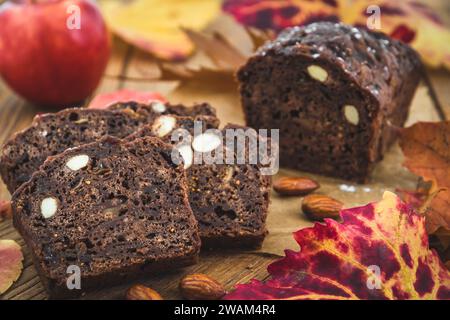 Herbstkuchen oder weihnachtskuchen mit Äpfeln auf einem Holzbrett, verziert mit farbigen Blättern Stockfoto