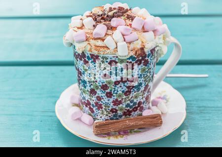 Heiße Schokolade mit Sahne und Marshmallows auf türkisfarbenem Holztisch Stockfoto