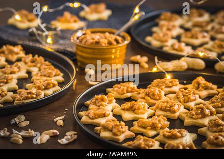 Hausgemachte sternförmige Kekse mit Nusskaramell auf Holzboden Stockfoto