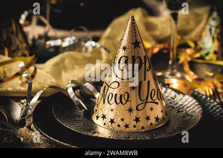 Tisch für Silvesterparty mit goldenen und schwarzen Farben, zwei Gläsern Sekt und Luftschlangen Stockfoto