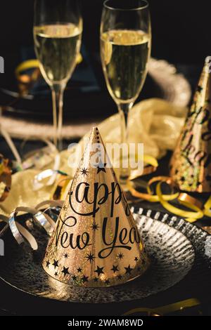 Tisch für Silvesterparty mit goldenen und schwarzen Farben, zwei Gläsern Sekt und Luftschlangen Stockfoto