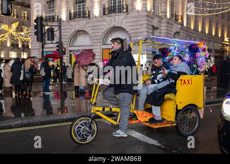 LONDON, UK - 16. Dezember 2023 : Ein Mann, der auf einer Rikscha reitet und ein glückliches Paar auf dem Rücken einer Straße in London Stockfoto