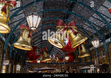 London, UK - 8. November 2023: Covent Garden Market mit Weihnachtsdekoration. Große Glocken und Kugeln hängen vom Dach. Die Leute sind einkaufen und sitzen Stockfoto