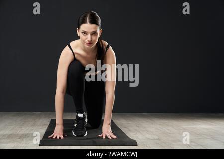 Entschlossene Sportlerin bleibt in der Hocke, bereit für den Start. Stockfoto