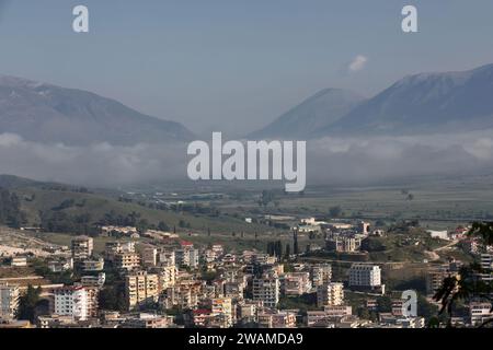 195 Panoramablick auf die unteren Gebäude am Hang des Massivs Mali i i Gjere, nebelbedecktes Tal des Drino Flusses. Gjirokaster-Albanien. Stockfoto