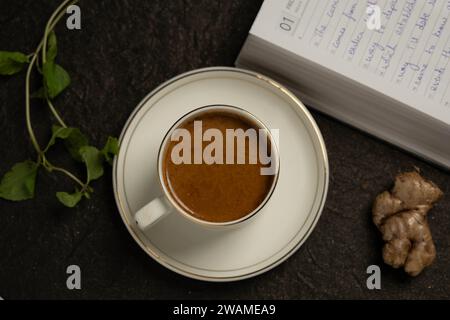 Eine Nahaufnahme einer weißen Kaffeetasse mit einem Buch auf einer Holzplatte Stockfoto