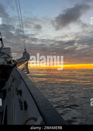 Orangefarbener Sonnenaufgang über dem Atlantik von einem hohen Schiffsbogen aus gesehen Stockfoto