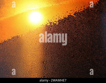 Natur-Hintergrund mit hellem Sonnenlicht, Wassertropfen und Eis Muster auf Winter Fensterglas Stockfoto