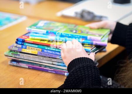 Bild von den Händen einer Bibliothekarin, während sie einen Stapel von Kinderbüchern durchsucht, die unscharf sind. Kinderbücher waren ein Schwerpunkt der Buchverbote Stockfoto