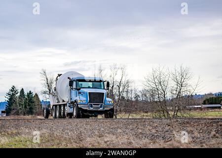 Industrieträger blaues Day Cab großer Lkw mit Betonmischer Auflieger für den Transport von Beton zur Bauseite Fahren auf dem schmalen L Stockfoto