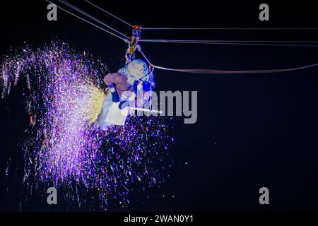 Latina, Italien. Januar 2024. Die Flying Befana streut glitzerndes Konfetti, als sie anlässlich der Epiphanienfeier in Latina vom Rathausturm absteigt. Hunderte jubelnde Kinder und Erwachsene begrüßten die Befana, die anlässlich der Epiphanienfeier in Latina vom Turm des Rathauses abstieg. Quelle: ZUMA Press, Inc./Alamy Live News Stockfoto