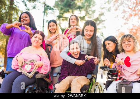 Internationaler Frauentag Inspiire Inspired Inclusion multiethnische Gruppen lieben Herz mit Händen. Rollstuhl Stockfoto