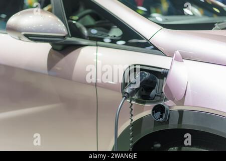 EV-Auto im Ruhezustand, verbunden mit einer Ladestation, verkörpert die nachhaltige Zukunft des städtischen Verkehrs. Das Stromkabel verbindet das Fahrzeug nahtlos Stockfoto