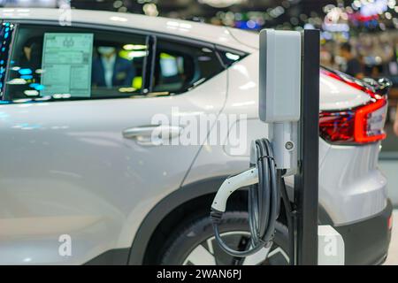 Das Elektrofahrzeug liegt an einer Ladestation und ist mit einem Stromkabel verbunden, das die umweltfreundliche Zukunft des städtischen Nahverkehrs in Aktion verkörpert. Stockfoto