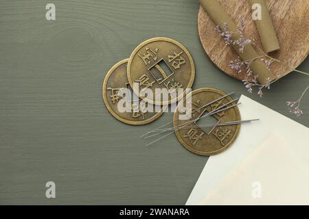 Akupunkturnadeln, Moxastöcke und antike chinesische Münzen auf grauem Holztisch, flacher Lay. Leerzeichen für Text Stockfoto