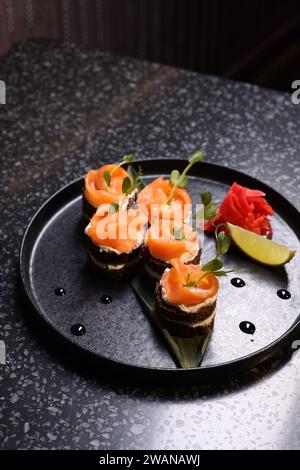Leckere Canapes mit Lachs, Frischkäse und Mikrogrün auf dunklem Tisch Stockfoto