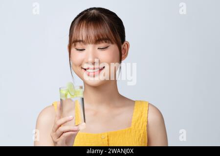 Angenehme Frau, die ein Glas Wasser mit Gurkenscheiben hält Stockfoto