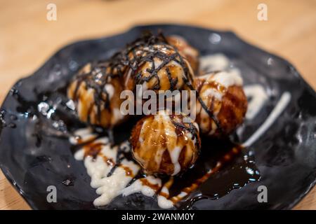 Takoyaki, Tintenfischbällchen, japanische Gerichte serviert auf Teller mit Sauce Stockfoto