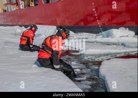 Antarktis. Dezember 2023. Der Petty Officer 1st Class Joshua Tangermann und der Petty Officer 2nd Class Harrison Bauer, die Kameraden des Bootswains, senken sich im Dezember im McMurdo Sound in der Antarktis ins Wasser, während sie Eisrettungstechniken üben. 29, 2023. Operation Deep Freeze ist eine von vielen Operationen im Indopazifik, bei denen das US-Militär die Sicherheit und Stabilität in der gesamten Region fördert. (Foto: Ryan Graves) (Foto: © U.S. Coast Guard/ZUMA Press Wire) NUR REDAKTIONELLE VERWENDUNG! Nicht für kommerzielle ZWECKE! Stockfoto