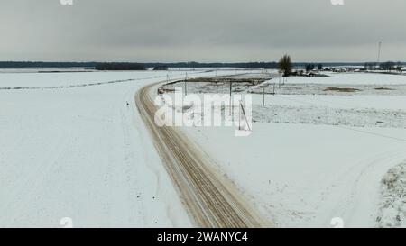Drohnenfotografie von kleinen ländlichen Feldwegen während des bewölkten Wintertages Stockfoto