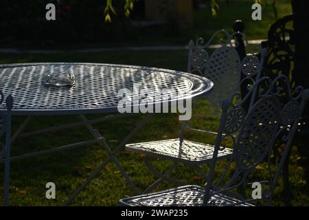 Der Charme des Gartens: Die Möbel sonnen sich in strahlendem Licht und laden zur Gelassenheit ein. Stockfoto