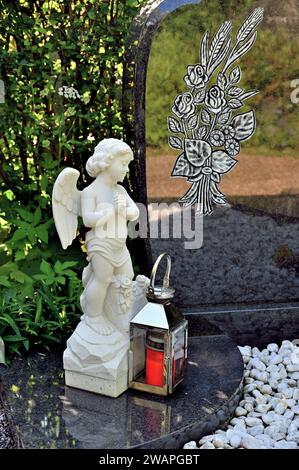 Weißer Engel und Grablaterne vor Grabstein Stockfoto