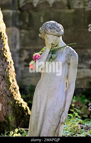 Trauernde Frauenskulptur mit einer Rose Stockfoto