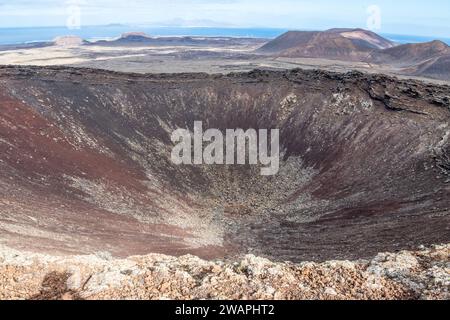 Calderon Hondo, Vulkan, Blick vom Calderón Hondo liegt auf dem nördlichen Ende der Insel Fuerteventura im Atlantischen Ozean. Er gehört zu den Volcanes de Bayuyo, die eine von Südwest nach Nordost ausgerichtete Reihe von Schlackenvulkanen über eine Bruchlinie der Erdkruste bilden. Die Entfernung des Calderón Hondo bis zur Küste beträgt etwa fünf Kilometer. Fuerteventura Spanien Corralejo *** Calderon Hondo, Vulkan, Blick von Calderón Hondo befindet sich am nördlichen Ende der Insel Fuerteventura im Atlantik es gehört zu den Volcanes de Bayuyo, die eine Reihe von Schlackenvol bilden Stockfoto