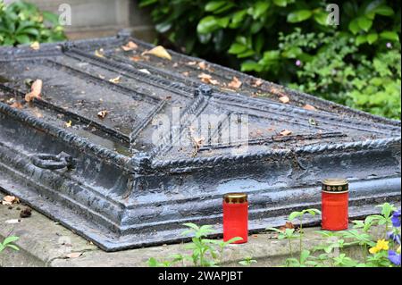 Alte bronzene Grabhülle mit zwei Grabkerzen im Vordergrund Stockfoto