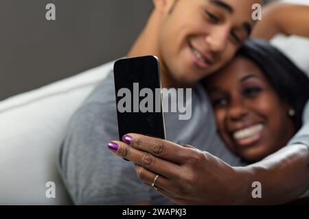 Intim und verspielt teilt ein Paar ein Lächeln und verewigt den Moment mit einem Smartphone Stockfoto