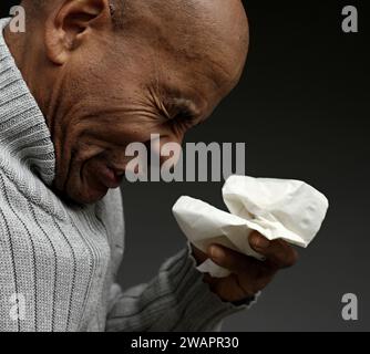 Blasen der Nase nach dem Fangen der Erkältung und Grippe mit grauem Hintergrund mit Menschen Stockfoto Stockfoto