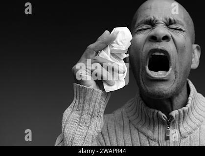 Blasen der Nase nach dem Fangen der Erkältung und Grippe mit grauem Hintergrund mit Menschen Stockfoto Stockfoto