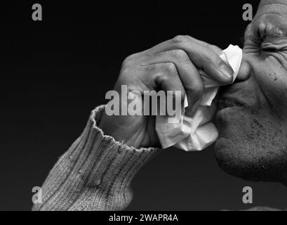 Blasen der Nase nach dem Fangen der Erkältung und Grippe mit grauem Hintergrund mit Menschen Stockfoto Stockfoto