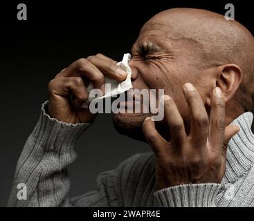 Blasen der Nase nach dem Fangen der Erkältung und Grippe mit grauem Hintergrund mit Menschen Stockfoto Stockfoto