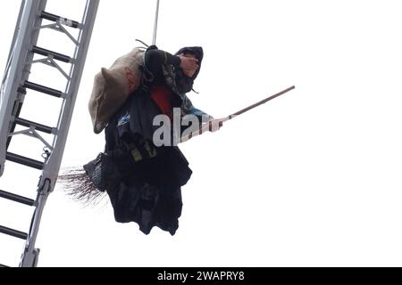 Caserta, Italien. Januar 2024. Ein als Befana getarnter Feuerwehrmann senkt sich von der Fassade des Königspalastes von Caserta ab und schenkt allen Kindern Süßigkeiten und Bonbons zum Abschluss der Weihnachtsfeiertage. Caserta, Italien, 6. Januar 2024. (Foto: Vincenzo Izzo/SIPA USA) Credit: SIPA USA/Alamy Live News Stockfoto