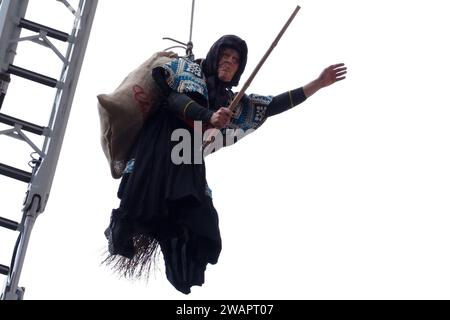 Caserta, Italien. Januar 2024. Ein als Befana getarnter Feuerwehrmann senkt sich von der Fassade des Königspalastes von Caserta ab und schenkt allen Kindern Süßigkeiten und Bonbons zum Abschluss der Weihnachtsfeiertage. Caserta, Italien, 6. Januar 2024. (Foto: Vincenzo Izzo/SIPA USA) Credit: SIPA USA/Alamy Live News Stockfoto